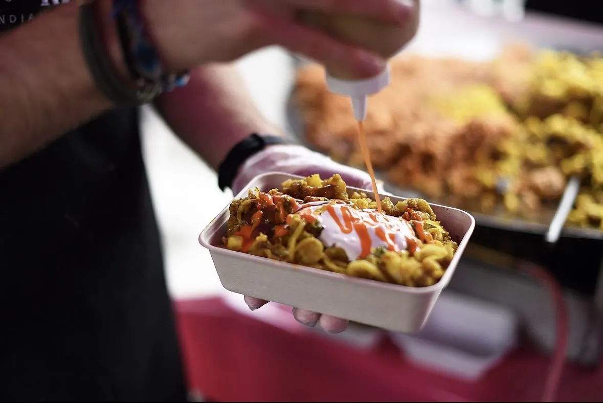 Mumbai Mix serving authentic Indian vegetarian street food, finishing a dish with sauce