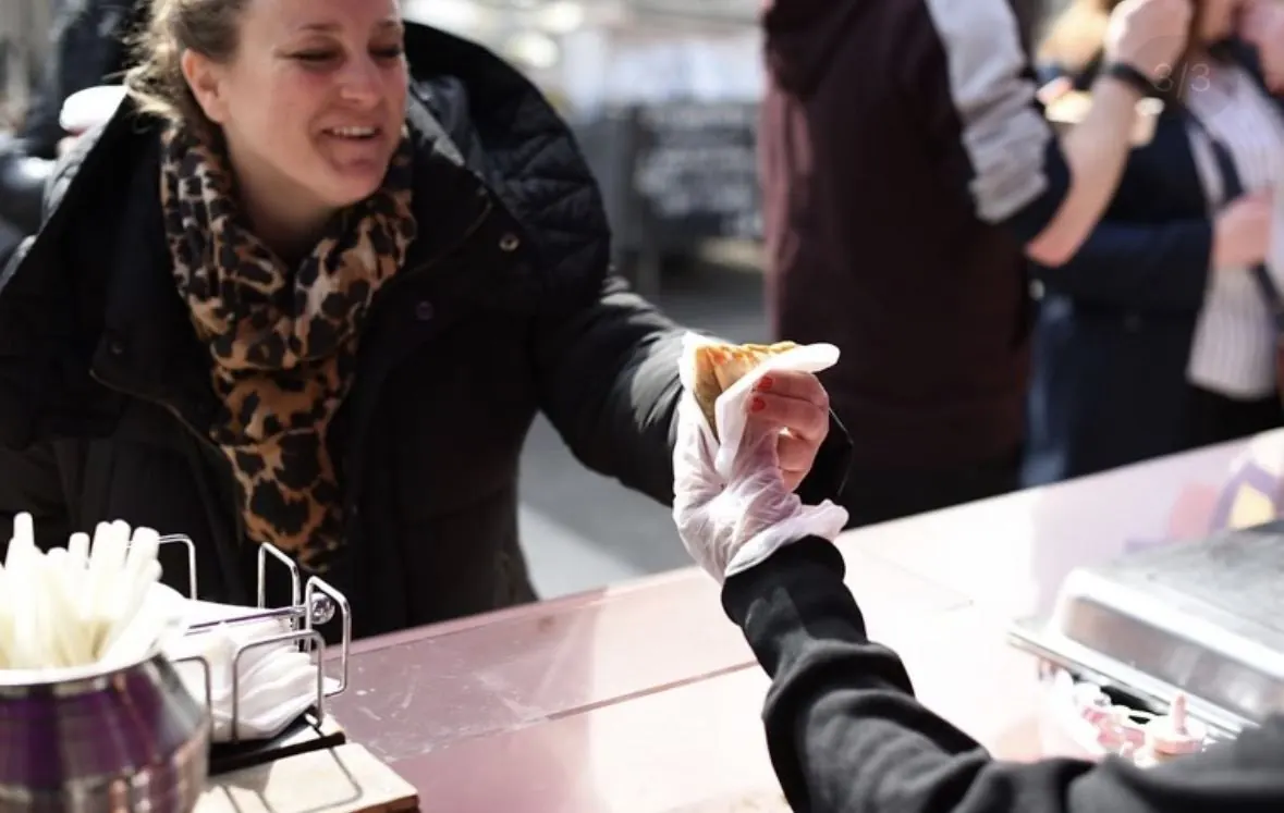 A customer being handed food wrapped in paper at a Mumbai Mix street food stall